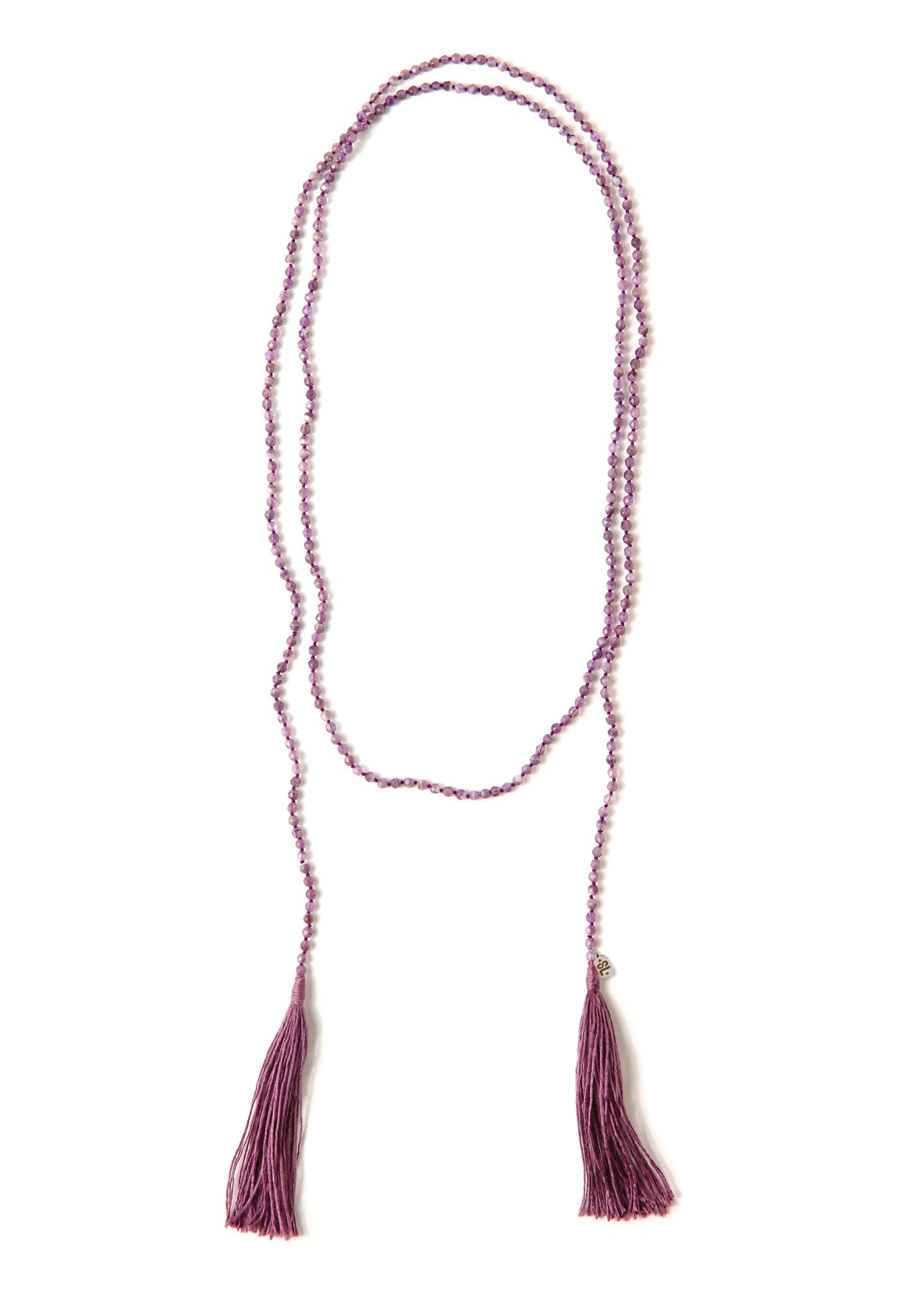 A Bohemian style Lariat Necklace, featuring 2 cotton tassels hanging from a long strand of natural, faceted amethyst stone beads, by Tribe Jewelry Designer Sarah Lewis.
