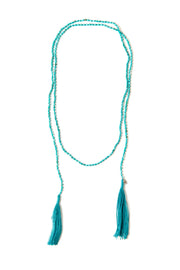 A Bohemian style Lariat Necklace, featuring 2 tassels hanging from a long strand of natural, faceted turquoise stone beads, by Tribe Jewelry Designer Sarah Lewis.
