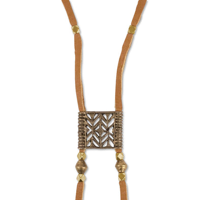 A Bohemian Bolo style necklace, featuring an antique bronze medallion, hanging on a long, brown leather cord, with brass beads, handmade by Tribe Jewelry Designer Sarah Lewis. 