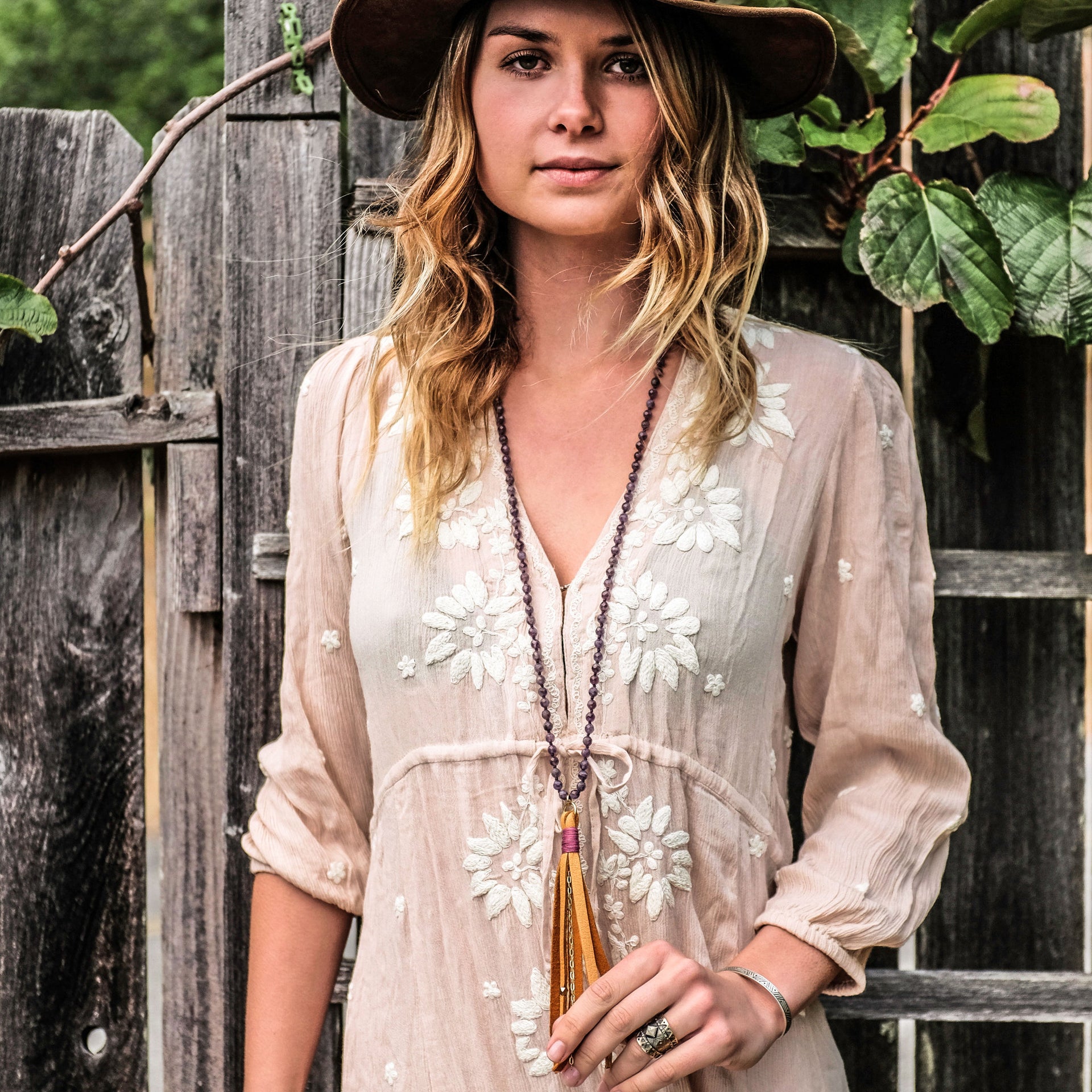 A Bohemian Mala style Necklace featuring a soft Suede Tassel, hanging from a strand of faceted Amethyst gemstone beads, handmade by Tribe Jewelry Designer Sarah Lewis. 