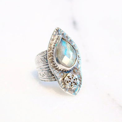 A one of kind ring featuring a faceted labradorite stone set in sterling silver, with snowflake and carved geometric design handmade by Tribe Jewelry Designer Sarah Lewis.