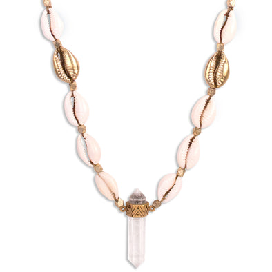 A Quartz Crystal set in Gold Plated Sterling Silver, hangs with natural and cast Cowrie shells, and Gold plated beads, on a long statement necklace, handmade by Tribe Jewelry Designer Sarah Lewis. 