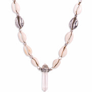 A Quartz Crystal set in engraved Sterling Silver, hangs with natural and cast Cowrie shells, and Silver beads, on a long, Bohemian Statement Necklace, handmade by Tribe Jewelry Designer Sarah Lewis. 
