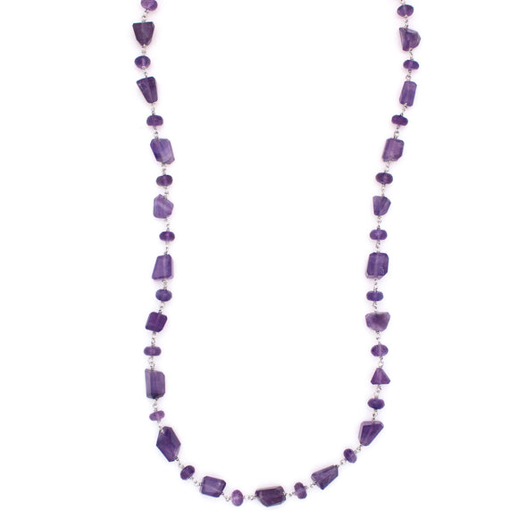 A Long Bohemian Beaded Necklace featuring Faceted Amethyst gemstones on a wire-wrapped chain, paired with an artisanal Silver plated chain, handmade by Tribe Jewelry Designer Sarah Lewis. 