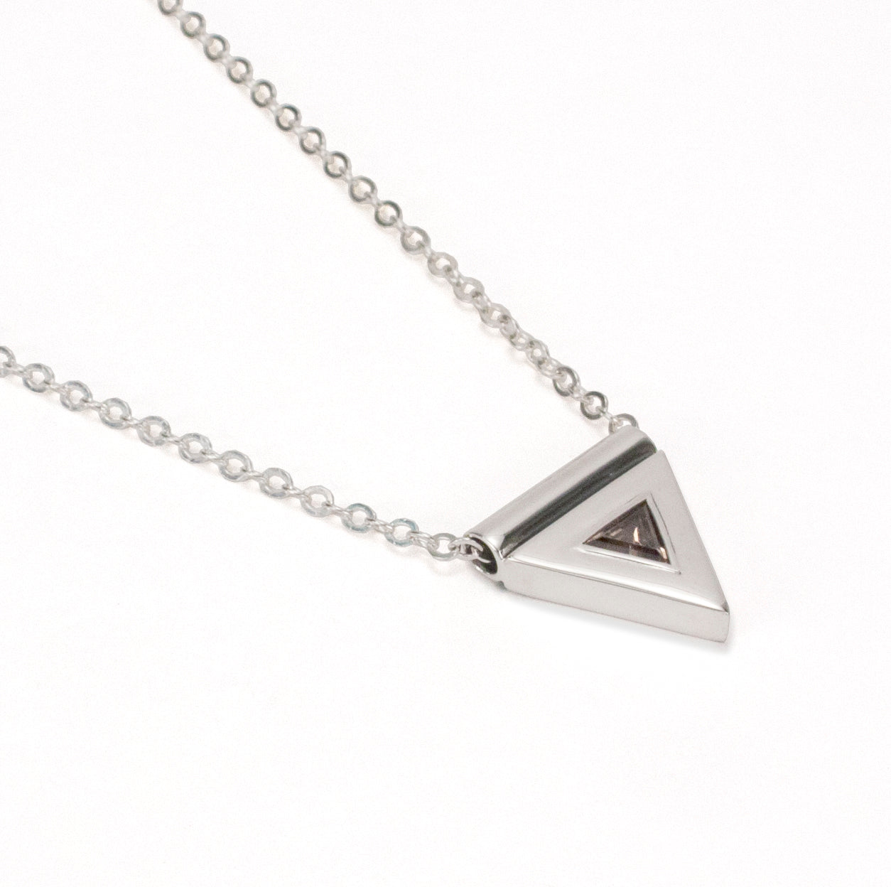 A sterling silver necklace, featuring a faceted, smokey quartz gemstone, in a triangular pendant, handmade by Tribe Jewelry Designer Sarah Lewis. 