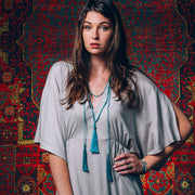 A Bohemian style Lariat Necklace, featuring 2 tassels hanging from a long strand of natural, faceted turquoise stone beads, by Tribe Jewelry Designer Sarah Lewis. 