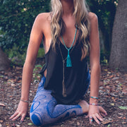 A Bohemian style Lariat Necklace, featuring 2 cotton tassels hanging from a long strand of natural, faceted labradorite stone beads, by Tribe Jewelry Designer Sarah Lewis. 