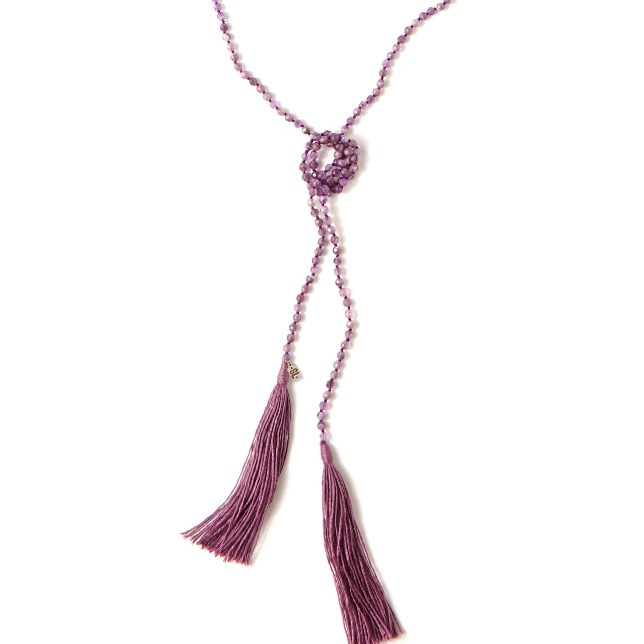 A Bohemian style Lariat Necklace, featuring 2 cotton tassels hanging from a long strand of natural, faceted amethyst stone beads, by Tribe Jewelry Designer Sarah Lewis.