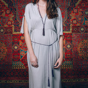 A Bohemian style Lariat Necklace, featuring 2 cotton tassels hanging from a long strand of natural, faceted amethyst stone beads, by Tribe Jewelry Designer Sarah Lewis. 