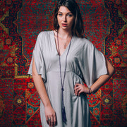 A Bohemian style Lariat Necklace, featuring 2 cotton tassels hanging from a long strand of natural, faceted amethyst stone beads, by Tribe Jewelry Designer Sarah Lewis. 