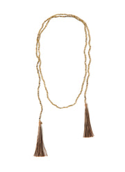 A Bohemian style Lariat Necklace, featuring 2 cotton tassels hanging from a long strand of natural, faceted labradorite stone beads, by Tribe Jewelry Designer Sarah Lewis. 
