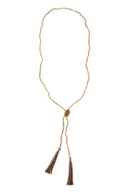 A Bohemian style Lariat Necklace, featuring 2 cotton tassels hanging from a long strand of natural, faceted labradorite stone beads, by Tribe Jewelry Designer Sarah Lewis. 