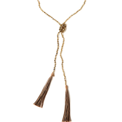 A Bohemian style Lariat Necklace, featuring 2 cotton tassels hanging from a long strand of natural, faceted labradorite stone beads, by Tribe Jewelry Designer Sarah Lewis. 