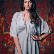 A Bohemian style Lariat Necklace, featuring 2 cotton tassels hanging from a long strand of natural, faceted labradorite stone beads, by Tribe Jewelry Designer Sarah Lewis. 