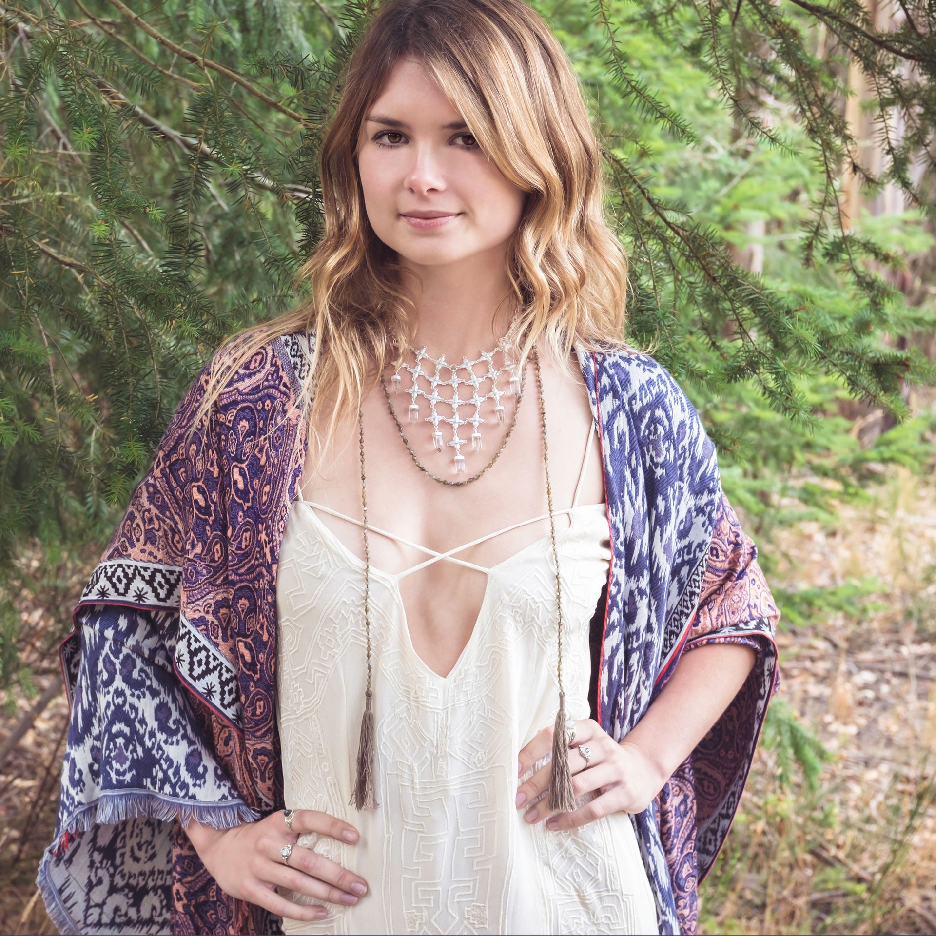 A Bohemian style Lariat Necklace, featuring 2 cotton tassels hanging from a long strand of natural, faceted labradorite stone beads, by Tribe Jewelry Designer Sarah Lewis. 