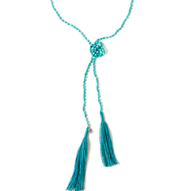 A Bohemian style Lariat Necklace, featuring 2 tassels hanging from a long strand of natural, faceted turquoise stone beads, by Tribe Jewelry Designer Sarah Lewis. 