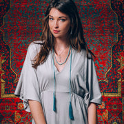 A Bohemian style Lariat Necklace, featuring 2 tassels hanging from a long strand of natural, faceted turquoise stone beads, by Tribe Jewelry Designer Sarah Lewis. 