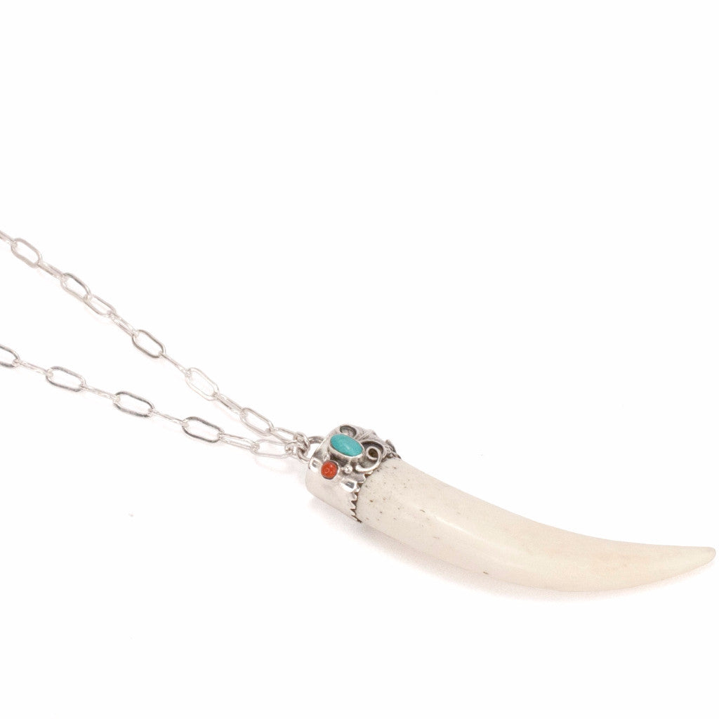 A Bohemian style Necklaces featuring a carved bone claw Pendant, set in a Sterling Silver end cap, with Turquoise and Coral stones, hanging on a long silver chain, handmade by Tribe Jewelry Designer Sarah Lewis. 