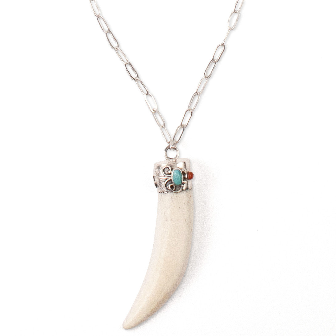 A Bohemian style Necklaces featuring a carved bone claw Pendant, set in a Sterling Silver end cap, with Turquoise and Coral stones, hanging on a long silver chain, handmade by Tribe Jewelry Designer Sarah Lewis.