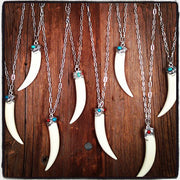 A Bohemian style Necklaces featuring a carved bone claw Pendant, set in a Sterling Silver end cap, with Turquoise and Coral stones, hanging on a long silver chain, handmade by Tribe Jewelry Designer Sarah Lewis. 